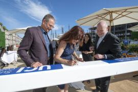 <p>UCI Chancellor Howard Gillman (far right) looks on as Henry and Susan Samueli sign a steel beam as part of the July 29 “topping off” ceremony. The celebration commemorated completion of the framing for the Susan &amp; Henry Samueli College of Health Sciences, which will impact health teaching and delivery in Orange County, across the country and around the world. Steve Zylius/UCI</p>
