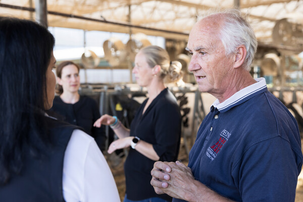 Four scientists speak in a dairy cow facility