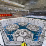 <p>A worker at the Daya Bay Reactor Neutrino Experiment site is perched near a water pool where four large detectors are submerged in this August 2012 photo. (Credit: Roy Kaltschmidt/Berkeley Lab)</p>

