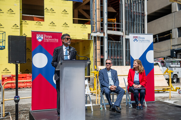 Dean Kumar at the podium with Stone and Magill on the stage