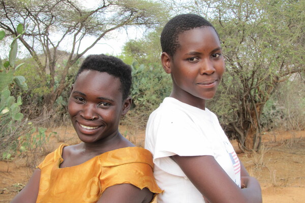 Two people from the Hadza group pose and smile outdoors