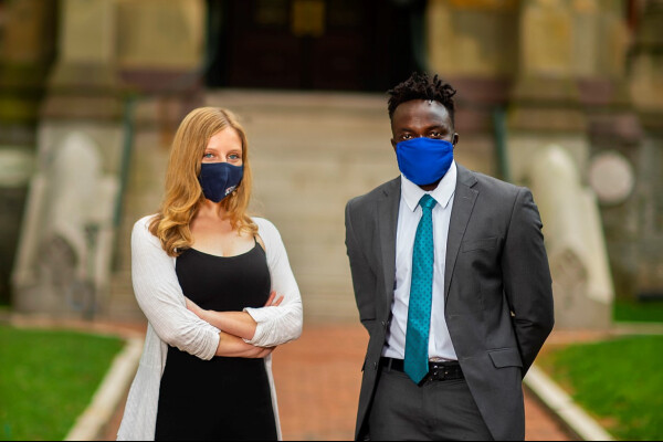 Leah Voytovich and Martin Leet in front of college hall while wearing masks