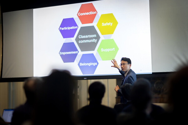 Daeyeon Lee points to a slide that reads 'Classroom community' while delivering a lecture.