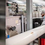<p>(Left): Two deformable mirrors. In addition to arrival time and pulse length control of both beam lines, these mirrors allow for independently shaping the focal spot mode, which is critical for optimized staged acceleration. (Right) In the newly-commissioned second beam line, the laser beam travels through the large white tubes into the laser-plasma accelerator vacuum system. Marlene Turner (foreground) and postdoctoral scholar Alex Picksley check for alignment. (Credit: Marilyn Sargent/Berkeley Lab)</p>
