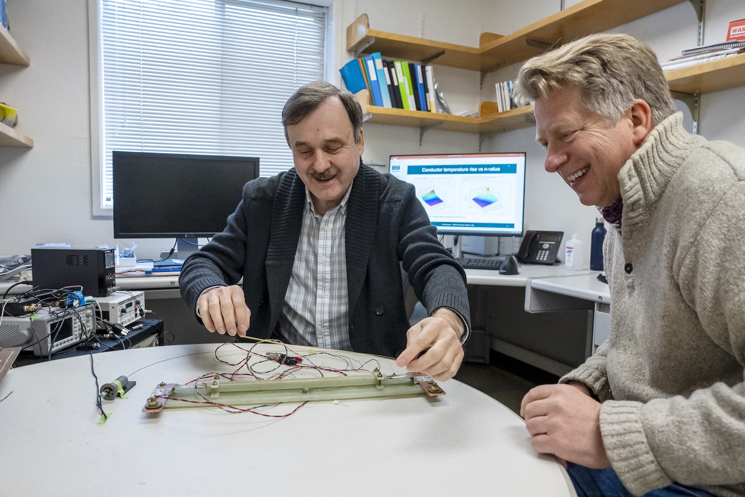 <p>Maxim Marchevsky (left) and Soren Prestemon discussing an experimental setup to test the sensitivity of a temperature monitoring system for a high temperature superconducting magnet. </p>

