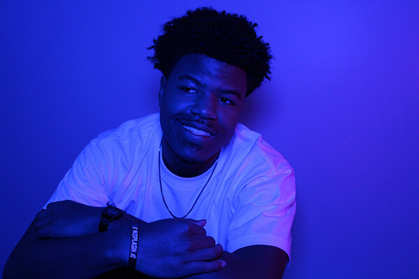 Niko Simpkins sitting with arms folded, smiling