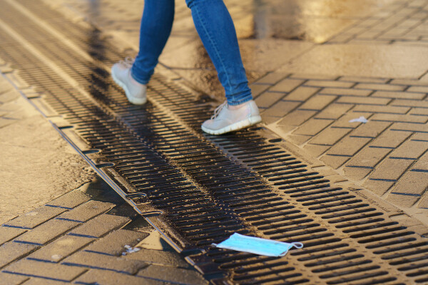 a person walking along a city street past a discarded mask